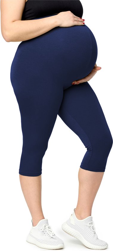 Een zwangere vrouw in een marineblauwe capri-legging en witte sportschoenen.