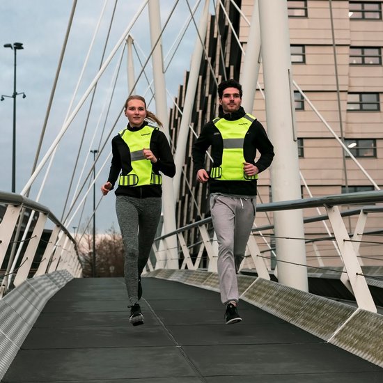 Man en vrouw joggend op een brug, beiden met een fluoriserend geel Tunturi reflectiehesje.