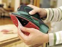 Handen bevestigen een rood schuurpapier aan een groene Bosch PSM 100 A multischuurmachine.