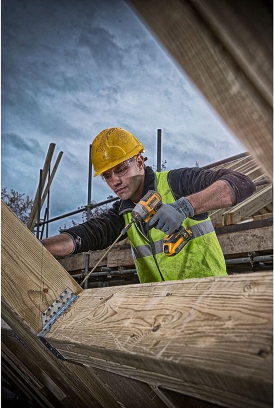 Man met geel-zwarte DeWalt slagschroevendraaier aan het werk op een bouwplaats met houten balken.