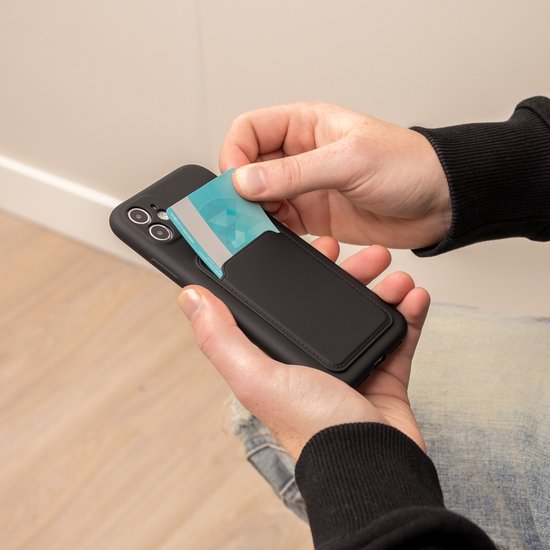 Handen voegen een kaart toe aan de zwarte hoes met kaarthouder op een iPhone.
