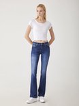 Vrouw in donkerblauwe LTB flared jeans en witte crop top.
