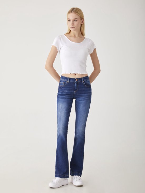 Vrouw in donkerblauwe LTB flared jeans en witte crop top.