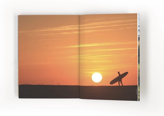 Silhouette van een surfer bij zonsondergang.
