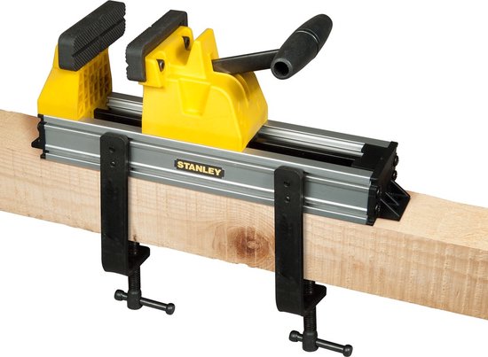 Gele Stanley bankschroef met zwarte klemmen, aan een houten balk, met hendel.