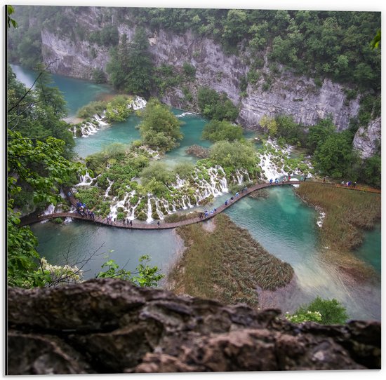 Vue aérienne de sentiers en bois serpentant à travers des cascades et des lacs turquoise dans une forêt luxuriante.