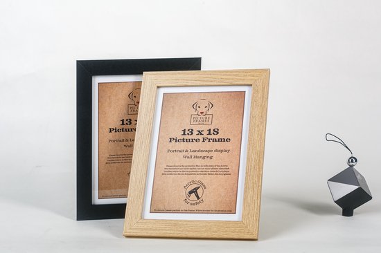 Zwarte en licht houten fotolijsten 13x18 cm naast elkaar, met decoratief zwart object.