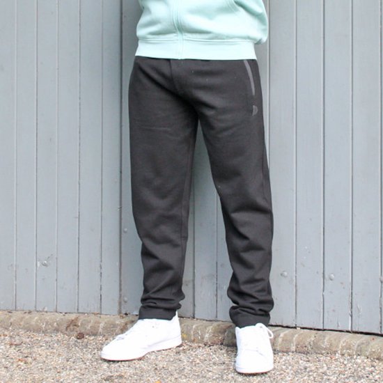 Man draagt een zwarte joggingbroek met witte sneakers.