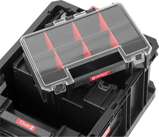 Zwarte Qbrick gereedschapskist met transparante deksel met rode verdelers, deels geopend.