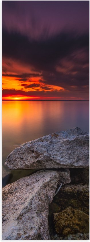 WallClassics - Poster Glanzend – Kleine Rotsen aan het Water met Zonsondergang - 30x90 cm Foto op Posterpapier met Glanzende Afwerking