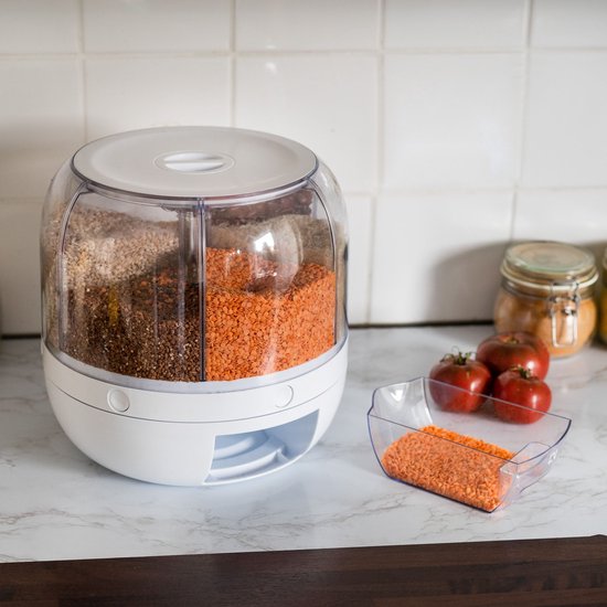 Witte voorraaddispenser met vier vakken gevuld met diverse granen en linzen op een aanrecht.