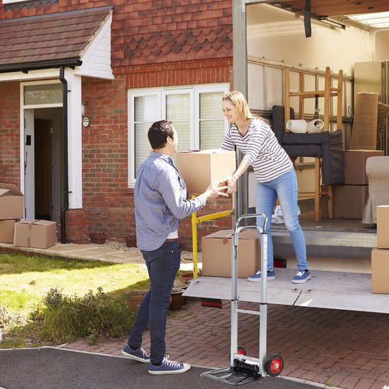 Man en vrouw laden dozen op een steekwagen bij een verhuiswagen.