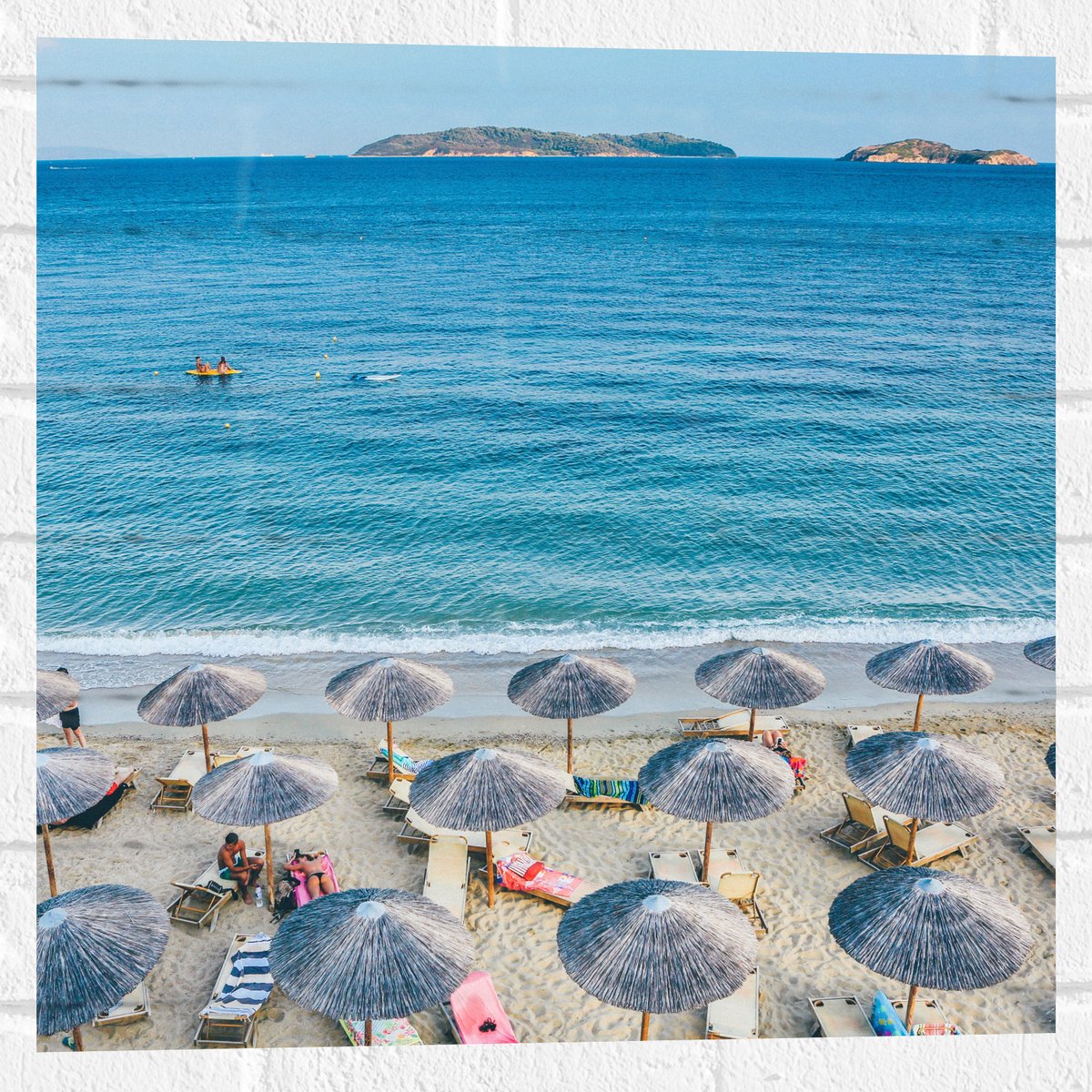 Muursticker - Rieten Parasols met Ligbedjes op het Strand - 50x50 cm Foto op Muursticker