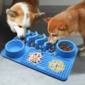 Twee honden eten van een blauwe siliconen snuffelmat met verschillende voedselvakken.