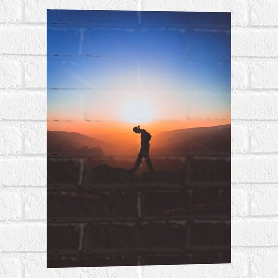 WallClassics - Muursticker - Silhouet Persoon tussen de Bergen bij Zonsondergang - 40x60 cm Foto op Muursticker