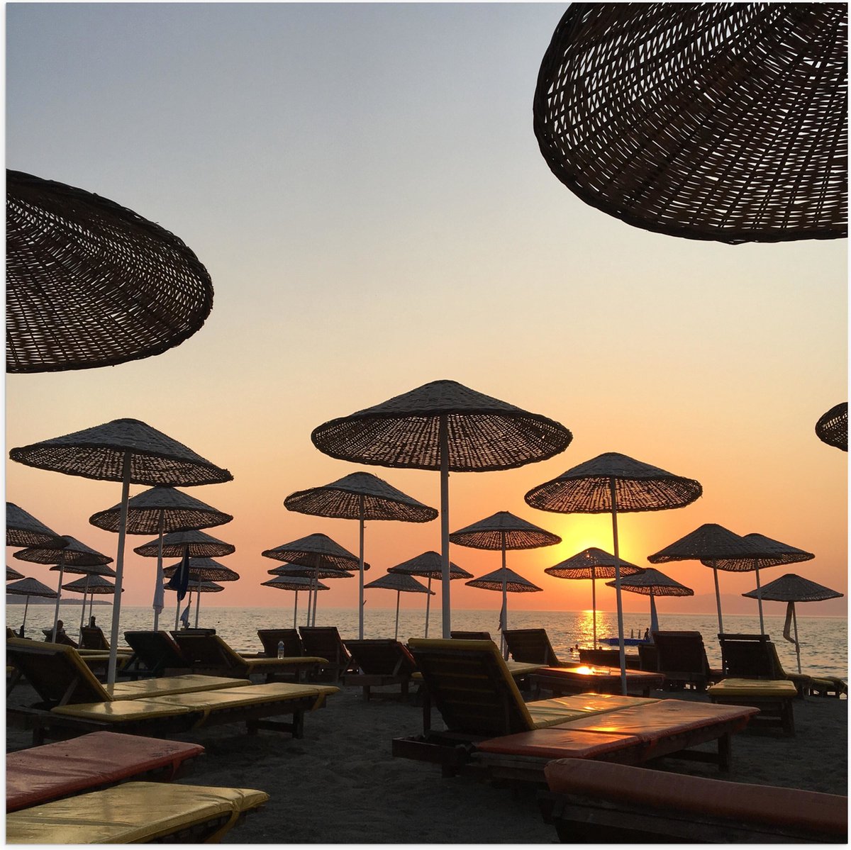 Poster Glanzend – Strand met Ligbedden en Rieten Parasols - 50x50 cm Foto op Posterpapier