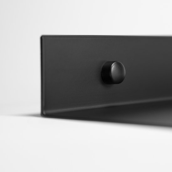 Gedetailleerde weergave van de hoek van een zwarte metalen wandplank met een ronde bevestiging.