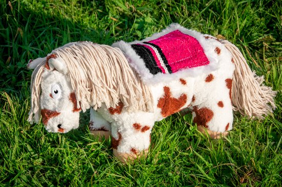 Wit pluche paardje met bruine vlekken en een roze zadeldekje met franjes.