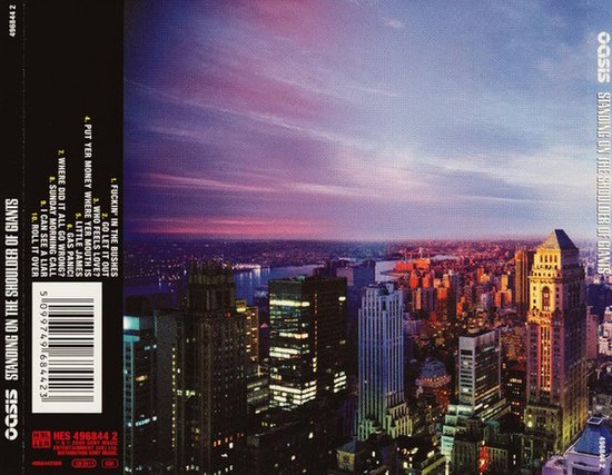 Le dos de la pochette du CD Oasis 'Standing On The Shoulder Of Giants' avec une vue sur la ville au coucher du soleil et une liste des pistes.