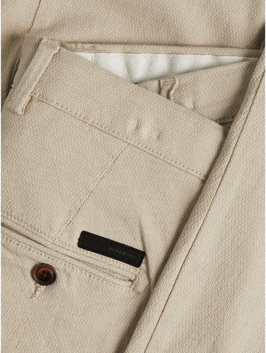 Detail van crèmekleurige chino broek met textuur, zakken en knoopsluiting, Jack & Jones logo.