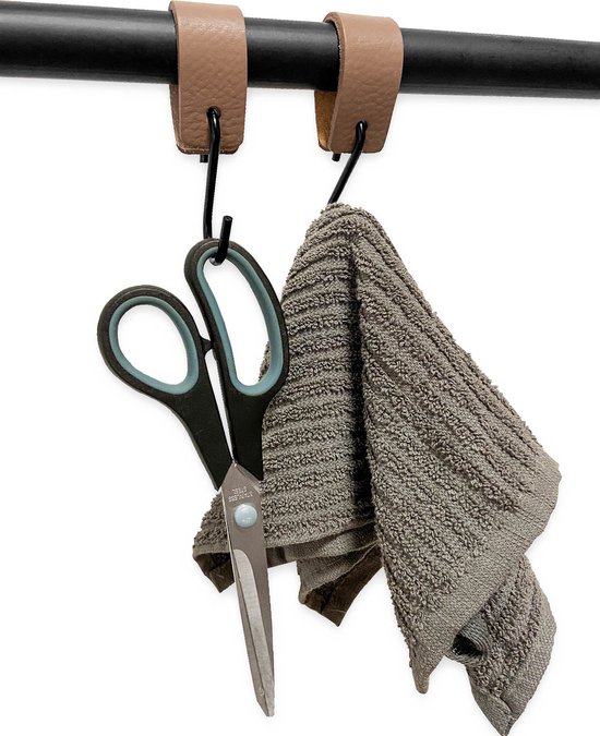 Bruine leren lussen met zwarte haken, waaraan een schaar en een grijze handdoek hangen.