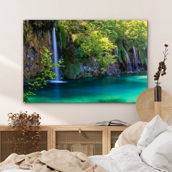 Een schilderij met de Plitvicemeren, waterval en turquoise water, hangend boven een bed.