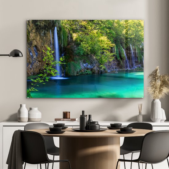 Een schilderij op acrylglas met de Plitvicemeren, een waterval en turquoise water, boven een eettafel.