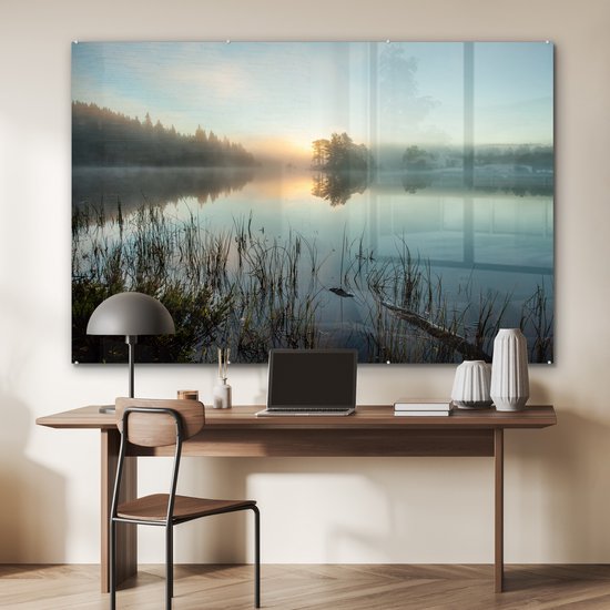 Une peinture sur verre d'un lever de soleil sur un lac brumeux, au-dessus d'un bureau avec un ordinateur portable.