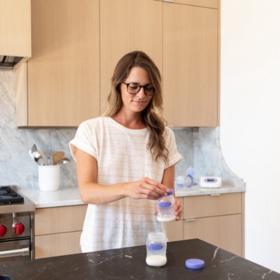 Een vrouw doet melk in een Lansinoh bewaar- of babyfles in een keuken.