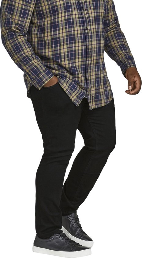 Model draagt een blauw met groen geruite blouse met lange mouwen en zwarte jeans.