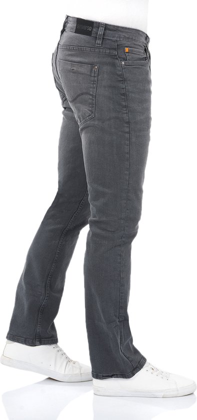 Zijaanzicht van een man in grijze bootcut jeans met witte sneakers.