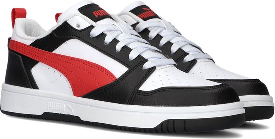 Twee witte sneakers met zwarte en rode details, Puma-logo op de tong en rode treklipjes.