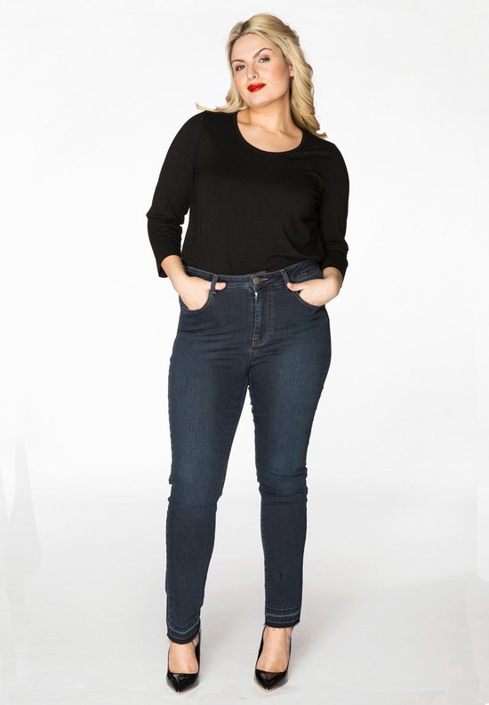 Model met donkerblauwe spijkerbroek met hoge taille, zwart shirt en zwarte hakken.