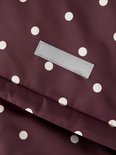 Detail van een label met 'name it' op een bordeauxrode jas met witte stippen.