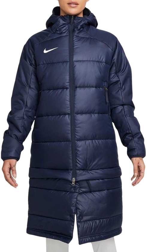 Donkerblauwe Nike winterjas met capuchon en witte swoosh. De jas valt tot over de knie en heeft horizontale quilting.
