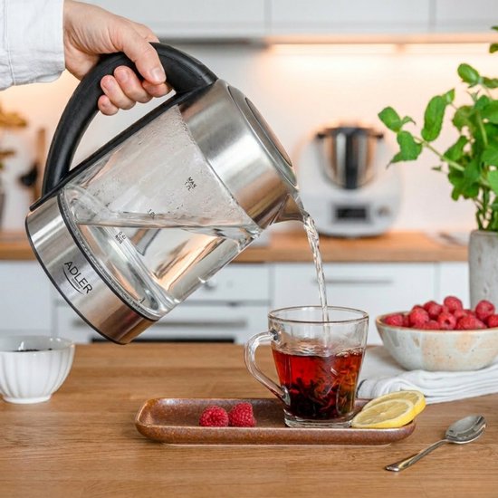 Glazen waterkoker met RVS details, schenkt thee in een glas.