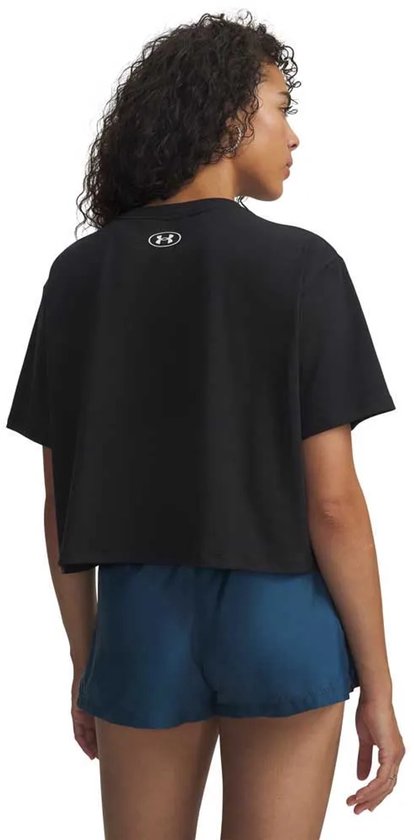 Zijzicht van een zwarte, cropped Under Armour T-shirt met wit logo gedragen door een model met blauwe shorts.