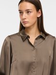 Close-up van taupe satijnen blouse met kraag en knoopjes.