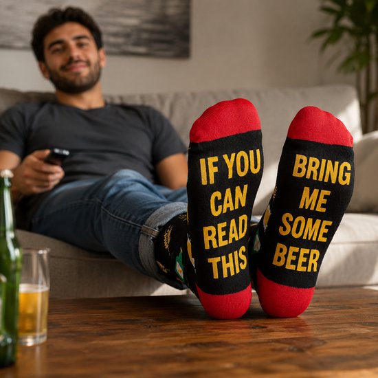 Voeten van een man met zwarte sokken die tekst 'IF YOU CAN READ THIS BRING ME SOME BEER' tonen.