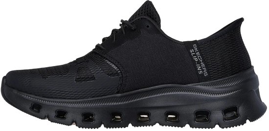 Zwarte Skechers damessneaker met mesh bovenwerk en een dikke, zwarte zool met uitsparingen. Slogan "SKECHERS SLIP-INS" op de zijkant.