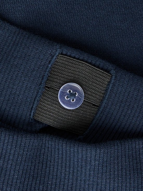 Sluiting met knoopje en elastiek aan de binnenkant van een donkerblauwe joggingbroek.