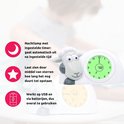 Witte schaap wekker met blauw hoofd. Groen display toont 7:00. Tekst en iconen: nachtlamp, sterren tellen af, USB/batterij.