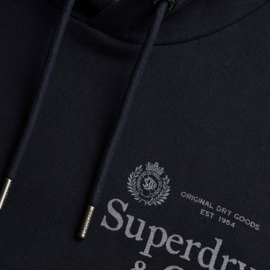 Detailopname van merklogo 'Superdry & Co' op donkerblauwe hoodie.