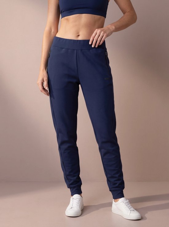 Vrouw in donkerblauwe sportbroek, met ritszakken aan beide zijden en merklogo op de heup.