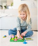 Een jong meisje speelt geconcentreerd met het spel Hans & Grietje op een wit tapijt. Het spel bevat een huisje, personages en ballen.
