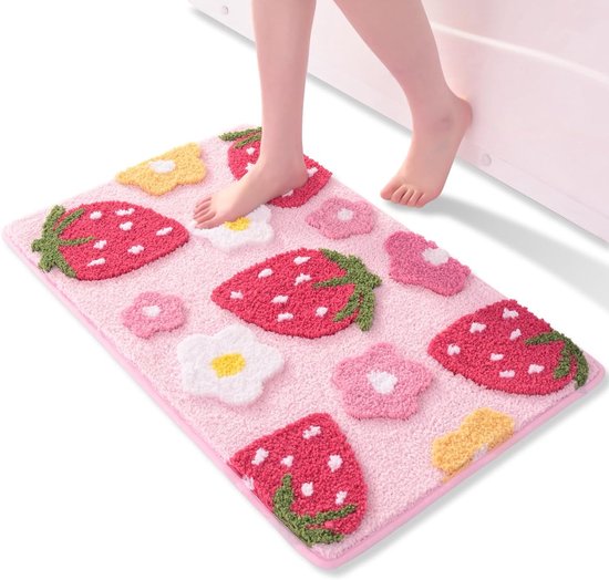Voet stapt op roze badmat met aardbeien en bloemen bij een badkuip.