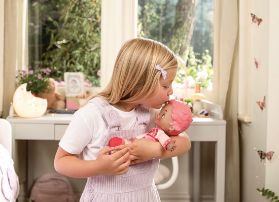Meisje met staartjes kust Luvibubs pop met roze haar en pyjama. Achtergrond is een kinderkamer.