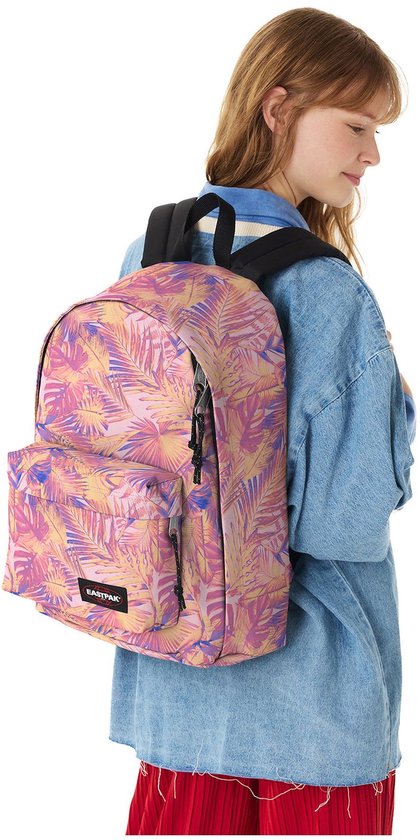 Vrouw draagt een roze rugzak met palmbladprint. De rugzak heeft een denim jasje en een rode rok.