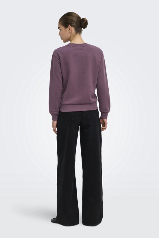 Vrouw van achteren gezien met paarse sweater en zwarte wijde jeans.