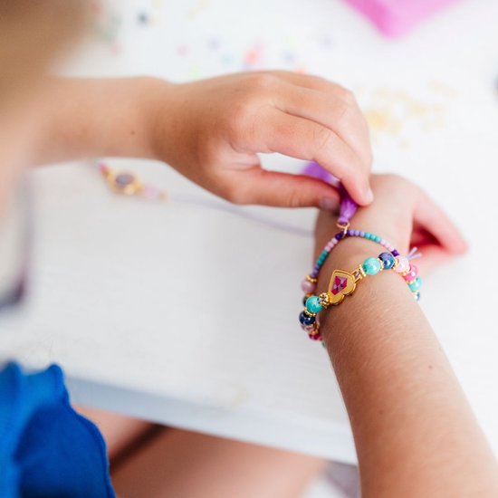 Kind maakt een kleurrijke armband met kralen en een unicorn bedel.
